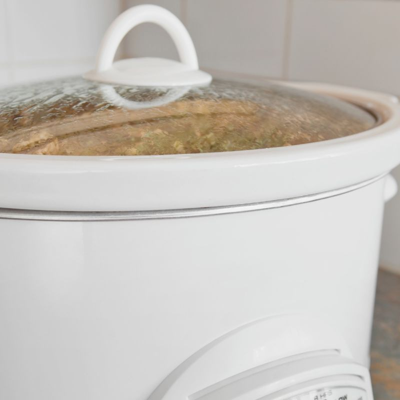white slow cooker sitting on a Kitchen counter with a white backsplash